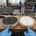 Side-by-side dirty and clean engine air filters on workbench with mechanic hands