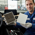 Mechanic holding dirty old cabin air filter next to clean new white filter