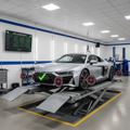 Vehicle on alignment rack with laser targets on all four wheels, digital screen showing green alignment specs